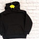 Black kid sweatshirt with a hood on white background top view. Fashionable unisex clothing, hoodie, casual youth style, sports. Blank hoody mock up